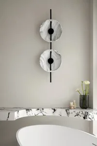 A minimalist bathroom featuring a marble countertop, white bathtub, and decorative vase.