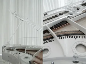 A modern, transparent grand piano in a white room with vertical blinds.