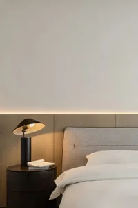 A minimalist bedroom featuring a grey upholstered headboard and white bedding.