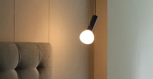 A modern bedroom featuring a ceiling-mounted light fixture with a taupe fabric shade hanging from a black, angled pendant.