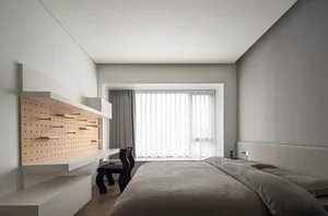 A minimalist bedroom featuring wooden storage units and a large bed with grey bedding.