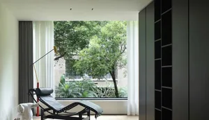 Modern living room with glass walls enclosing lush greenery.