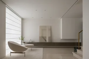 A living room with minimalist design featuring concrete and glass elements.