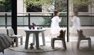 A modern playroom featuring concrete furniture and colorful toys on a round rug.