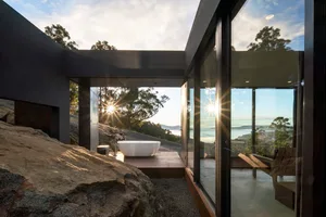 Modern bathroom featuring a glass-enclosed bathtub and a wooden deck