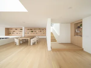 A modern residential entryway featuring white wooden floors, minimalist design, and a combination of white and beige elements