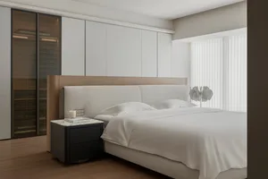 A modern minimalist bedroom featuring a white upholstered bed with a wooden headboard and a minimalistic decorative lamp on a