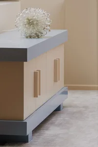 Modern minimalist design cabinet with a glass decorative ball on top, featuring wood handles and a sleek, light blue top.