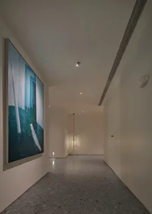 Modern interior design featuring a corridor with concrete flooring and a painting depicting a sailboat.
