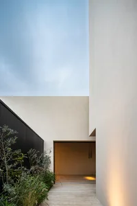 Image of a modern residential entryway with concrete walls and a small garden.