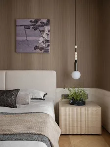 A modern bedroom featuring a textured wood headboard on a white upholstered bed, with a minimalist design aesthetic.