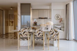 A modern dining room with a marble table and chairs with a geometric pattern.