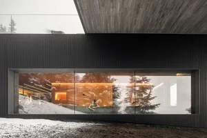 A modern house with a concrete roof and glass walls, featuring a wooden interior with a cozy atmosphere.