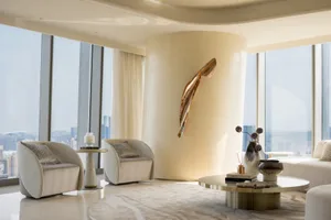A modern living room featuring sleek glass and concrete elements with a metal sculpture.