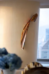 A vibrant, metallic sculpture hanging on a wall, reflecting light and adding a contemporary touch to the room.