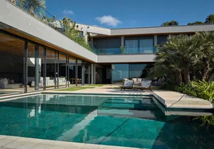 Modern residential architecture featuring glass walls and a pool.