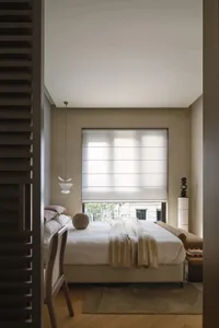A serene minimalist bedroom featuring soft textiles on the bed and wooden flooring.