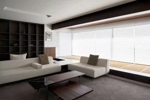 A minimalist living room with concrete furniture and large windows.