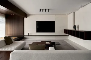 A modern minimalist living room featuring metal, concrete, and leather elements.