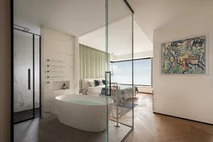 Modern bathroom featuring a freestanding bathtub, glass shower enclosure, and wooden flooring.