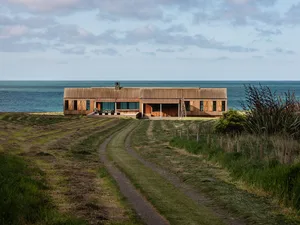 A modern beach house with wooden exterior and ocean view.
