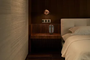 Modern bedroom featuring a wooden nightstand, bed with a headboard, and minimalistic decor.