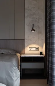 Minimalist bedroom with a modern upholstered headboard on a bed frame, illuminated by a hanging lamp, and a nightstand with a