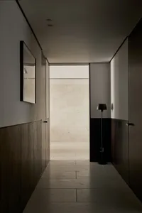 A minimalist corridor with wooden walls and a floor lamp.
