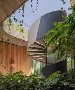 A modern interior featuring a metal spiral staircase surrounded by lush greenery.