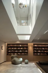 Modern minimalist library with wooden shelves displaying magazines, featuring a uniquely designed armchair and ball-shaped ob