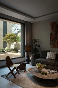 A living room with a gray leather sofa, a round marble coffee table, and a large window providing natural light.