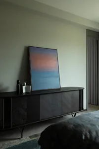 A modern bedroom featuring a black wooden console with a large abstract painting and sculptures.