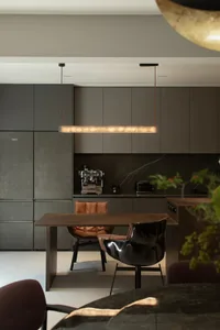 A modern kitchen with marble countertops and cabinets, featuring a dining table and chairs.