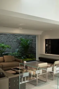 A modern industrial living room with concrete walls and plants.