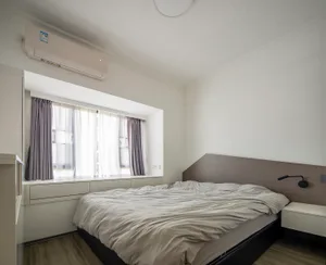 A minimalist bedroom with a bed, curtains, and a window.