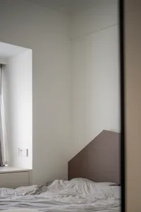 Unmade bed with grey headboard in minimalist bedroom