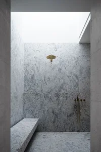 Modern bathroom featuring granite walls and marble shower bench