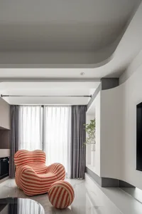 A modern living room with a striped armchair and ottoman, featuring glass and fabric materials.