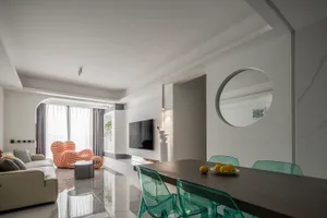 A modern living room with white marble flooring, a beige sofa, and green plastic chairs.