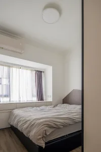 A minimalist bedroom with a bed, curtains, and a ceiling light fixture.