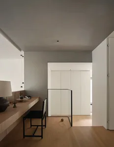 A minimalist residential interior featuring light wood, glass, and metal elements.