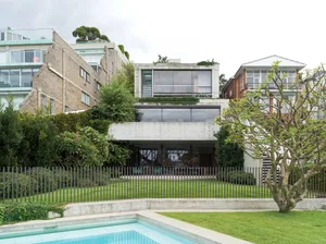 A modern residential home exterior showcasing a concrete facade with large glass windows and a rooftop garden.
