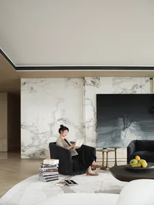A minimalist living room with a marble accent wall and modern furniture.