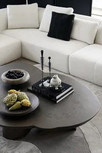 A modern living room with a large sectional sofa, a unique concrete coffee table, and decorative elements such as a fruit bow
