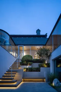 Modern minimalist residential interior with stone and glass elements at night.