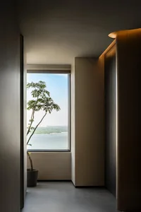 A minimalist hallway features a large window offering a scenic water view.