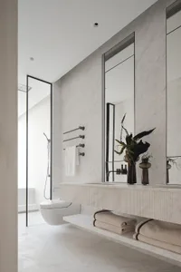 Modern bathroom interior featuring white marble walls and floor, a floating vanity, and a walk-in shower.