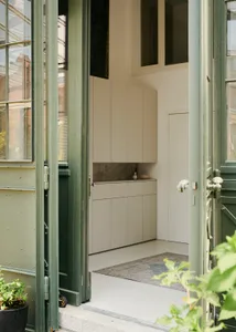 A modern apartment entryway featuring white walls, doors, and cabinets.