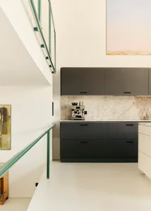 A modern kitchen featuring marble countertops and black cabinets.