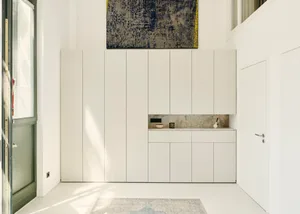 Modern minimalist kitchen with white cabinets and marble countertops and backsplash.
